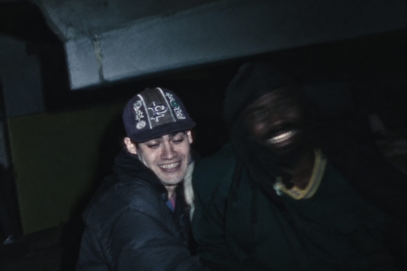 Two men laughing under a concrete underpass at night, still from Archy Moor “Robbery Rings”